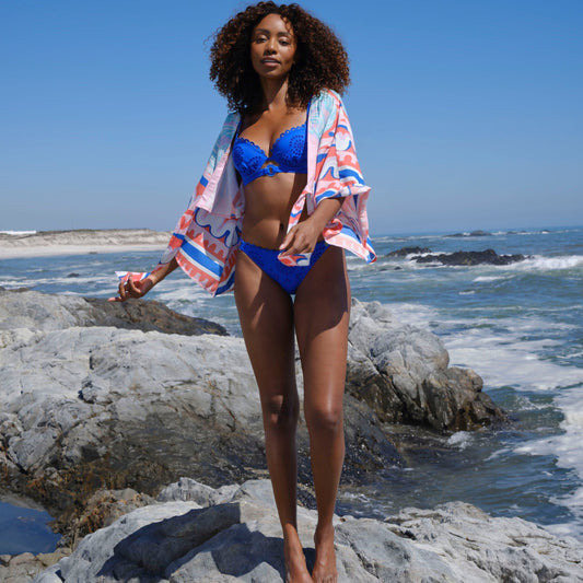 Woman wearing electric blue broderie bikini with pink palm print, short kimono tie front top cover up